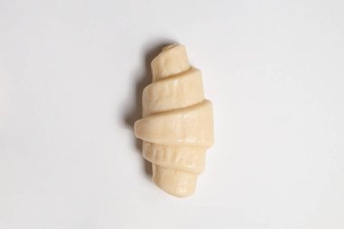 Beyaz arka planda izole edilmiş kruvasan pişirmeye hazır yarı donmuş halde stüdyo çekimini kapat. Pişmemiş geleneksel Fransız pastası. Boşluğu kopyala, üst görünüm.