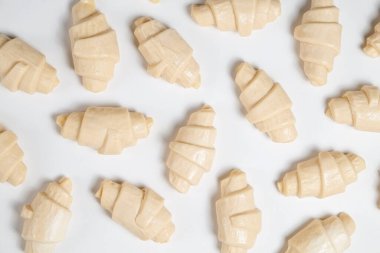 Beyaz arka planda izole edilmiş kruvasan pişirmeye hazır yarı donmuş halde stüdyo çekimini kapat. Pişmemiş geleneksel Fransız pastası. Boşluğu kopyala, üst görünüm.