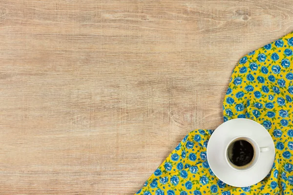Coffee on pattern flower cloth napkin on empty wooden background