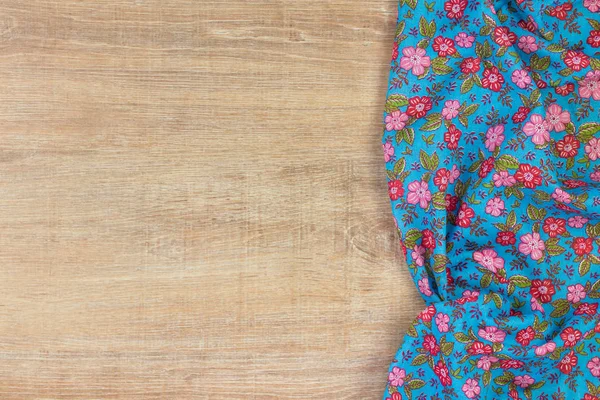 Floral pattern cloth napkin on empty wooden background.