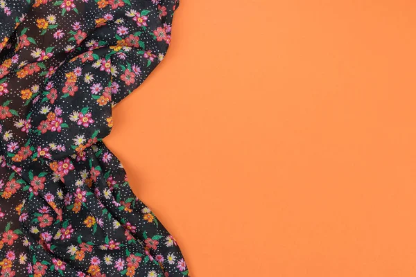 Floral pattern tablecloth on empty orange background. Top view w — Stock Photo, Image