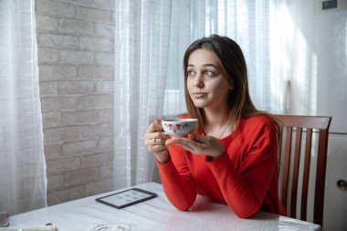 Mutfaktaki masada dijital kitap okuyan bir kız.