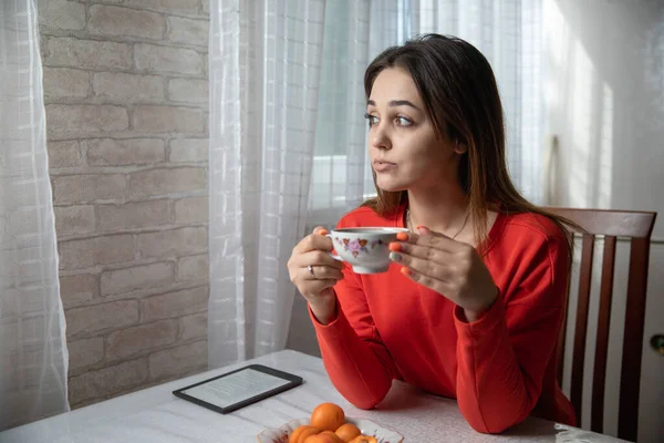 Mutfaktaki masada dijital kitap okuyan bir kız.