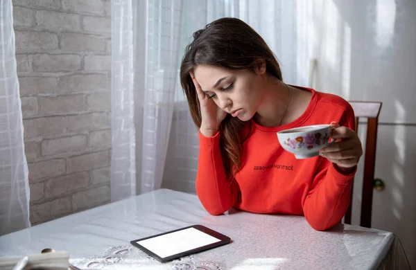 Girl reading a digital book at a table in the kitchen