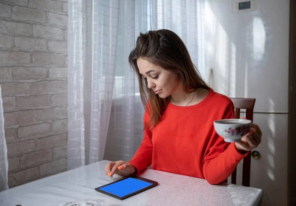 Girl reading a digital book at a table in the kitchen