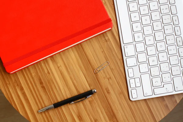 wooden office desk top view with red notebook