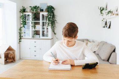 Corona salgını yüzünden karantina zamanında ev ödevi yapan çalışkan okul çocuğu. Çocuklar için eğitim ve uzak mesafe eğitimi. Karantina sırasında evde eğitim. Evde eğitim kavramı