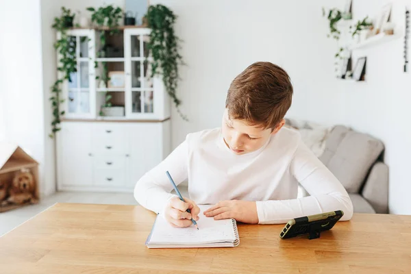 Hard-working school kid boy making homework math during quarantine time from corona pandemic disease. Education and distance learning for kids. Homeschooling during quarantine. Homeschooling concept