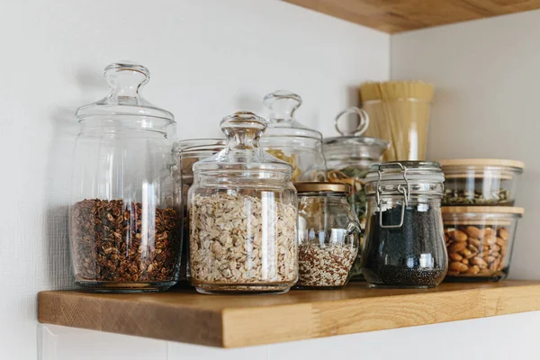 Mutfaktaki raflarda cam kavanozlarda çeşitli tahıl ve tohumlar var. Mutfak dahili fikirleri. Çevre dostu mutfak, sıfır atık ev konsepti