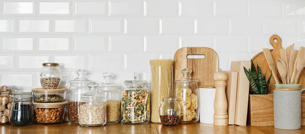 Mutfaktaki ahşap masadaki cam kavanozlarda çeşitli mısır gevrekleri ve tohumlar. Mutfak dahili fikirleri. Çevre dostu mutfak, sıfır atık ev konsepti