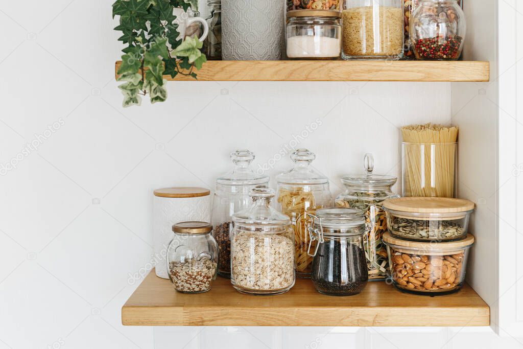Various cereals and seeds in glass jars on the shelves in the kitchen. Kitchen interior ideas. Eco friendly kitchen, zero waste home concept