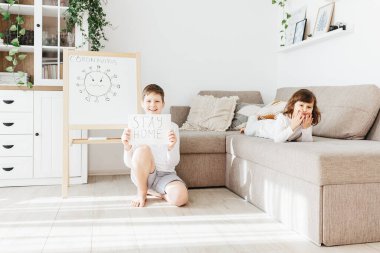 Gülen çocuk Pozitif Kalın 'ı tutuyor ve üzgün kız karantina sırasında kanepede yatıyor. Coronavirus konsepti