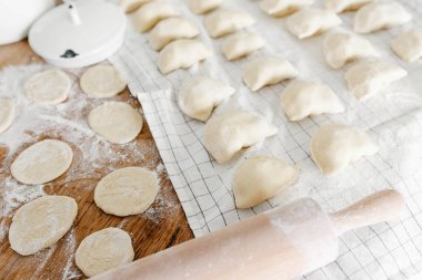Mutfaktaki ahşap masanın üzerinde patates ve soğanlı çiğ ev yapımı hamur köftesi. Varenyky pierogi yapma süreci geleneksel Ukrayna yemeği