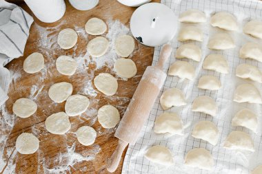 Mutfaktaki ahşap masanın üzerinde patates ve soğanlı çiğ ev yapımı hamur köftesi. Varenyky pierogi yapma süreci geleneksel Ukrayna yemeği