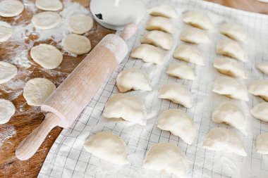 Mutfaktaki ahşap masanın üzerinde patates ve soğanlı çiğ ev yapımı hamur köftesi. Varenyky pierogi yapma süreci geleneksel Ukrayna yemeği