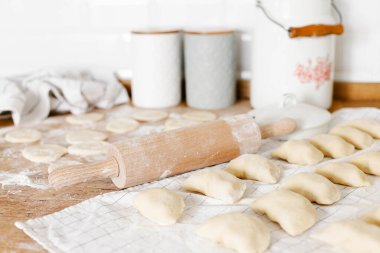 Mutfaktaki ahşap masanın üzerinde patates ve soğanlı çiğ ev yapımı hamur köftesi. Varenyky pierogi yapma süreci geleneksel Ukrayna yemeği