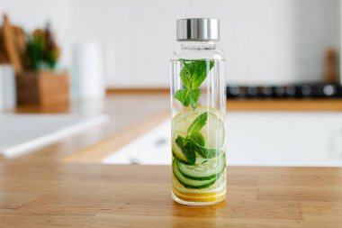 Arka planda cam şişe mutfaktan salatalık, limon ve nane ile detoks yaptım. Tek kullanımlık plastik yerine cam boll kullanma sıfır israf yaşam biçimi kavramı