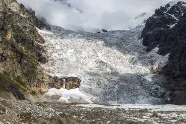 Güneşli bir günde Svaneti Georgia 'nın dağlarından küçük şelale manzaralı dev Lardaad buzulu.