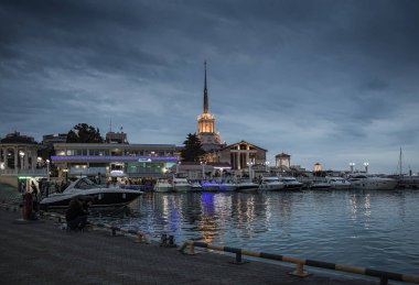 Sochi şehir teknelerle Körfezi kıyısında ışıklı bir kulenin kurşun bulutlar ile kaplı gökyüzü delip geçiyor.