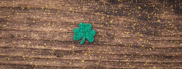 St Patrick day background with shamrock clover leaf on wood, Irish festival symbol, toned, with fairy dust texture, copyspace