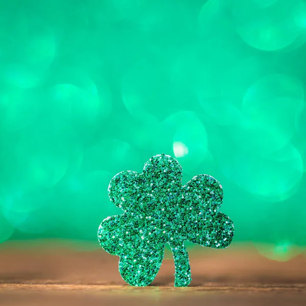 St Patrick day background with shamrock clover leaf on wood, Irish festival symbol, toned, with fairy dust texture, copyspace