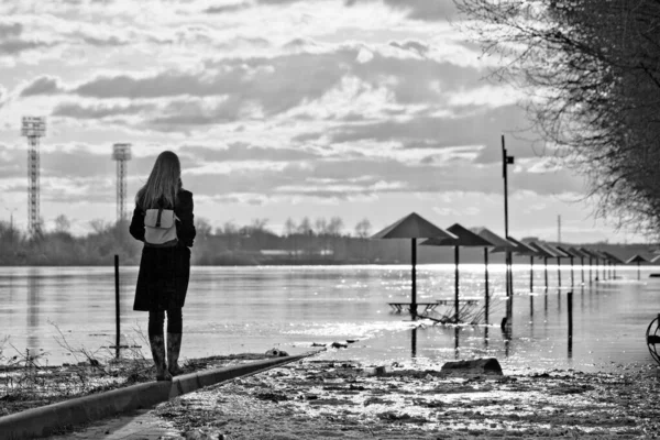 Urban landscape in early spring flood with young woman figure. Russia.