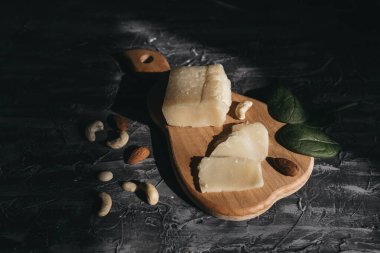 Tahta yağmurda dilimlenmiş parmesan peyniri ve fındık.