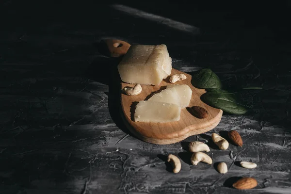Tahta yağmurda dilimlenmiş parmesan peyniri ve fındık.