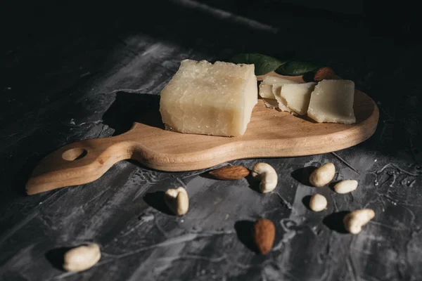 Tahta yağmurda dilimlenmiş parmesan peyniri ve fındık.