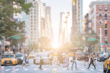 Manhattan 'da, arka planda güneş ışığıyla karşıdan karşıya geçen isimsiz insanlar.
