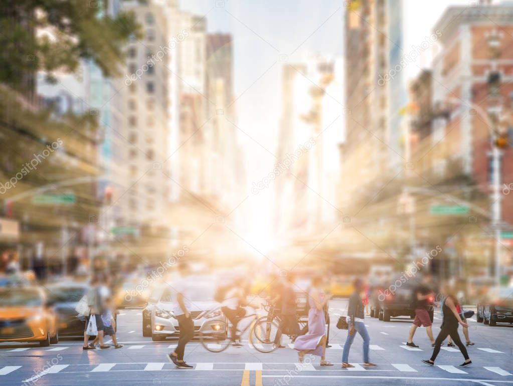 Anonymous people crossing street in Manhattan New York City with sunlight in background