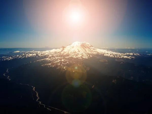 Bright sun in sky above mountain peak - aerial overhead view
