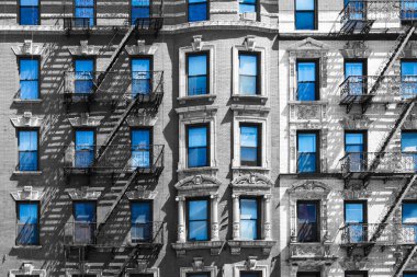 Mavi gökyüzü New York'ta siyah beyaz bir binanın pencerelerinde yansıyan