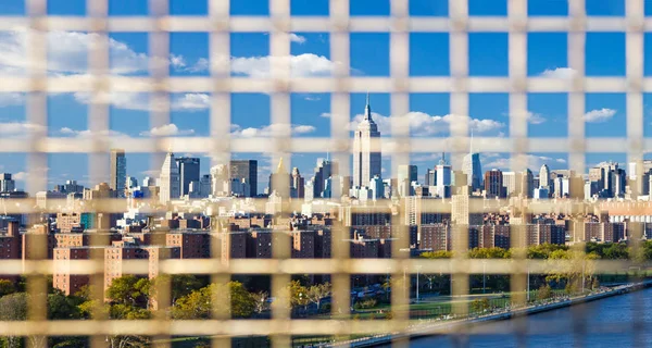 ブルックリンとマンハッタンの間のウィリアムズバーグ橋のフェンスの棒を通して見えるニューヨーク市のスカイライン — ストック写真