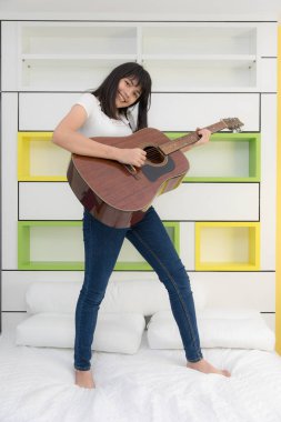 Asyalı kız yatak odasında gitar çalmak