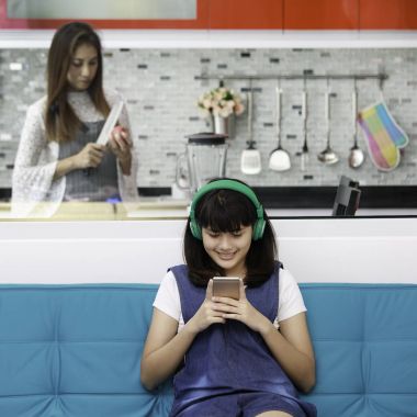 İki kişi, kızı oynamaya ve smartphone anne yemek yemek onun için süre bakarak