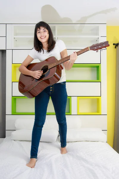Asyalı kız yatak odasında gitar çalmak — Stok fotoğraf