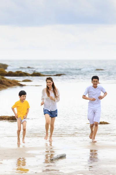 Asian family running on sand beach in cloudy day — Stock Photo, Image