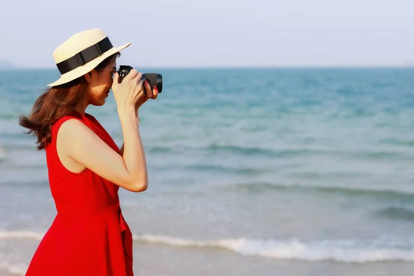 Χαμογελάστε Πρόσωπο Γυναίκα Φωτογράφος Κόκκινο Φόρεμα Στέκεται Στην Παραλία Και — Φωτογραφία Αρχείου