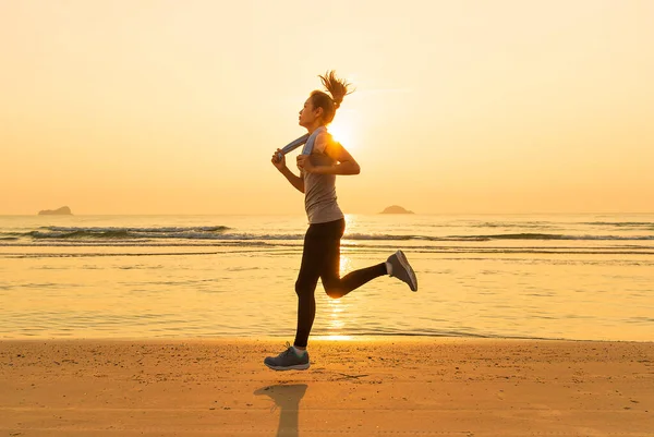 黎明时分 一个身材匀称的女人在海滩上奔跑 现代人健康与重体能训练的概念 — 图库照片