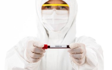 Steriliz laboratuvar önlüğü giyen bilim adamı elinde Covid-19 test tüpü örneği tutuyor. Virüsün adı üzerine seçici odaklanma. Coronavirüs 'ü yenmek için araştırma yapan tıp insanları için konsept.
