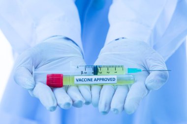 Üzerinde steteskop bulunan doktor önlüğü ya da laboratuvar önlüğü giyen insanların elinde Covid-19 aşısı var. Araştırmada başarılı olma ve tıp insanlarının koronavirüsünü kazanmaya çalışma fikri..