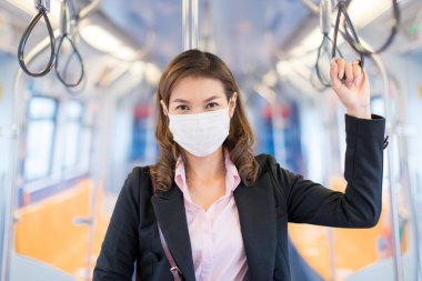 Tıbbî hijyen maskesi takan eğitimli Asyalı iş kadını yolcu. Ayakta, halkayı metronun içinde ya da büyük şehirde trenle gidip gelen biri. Coronavirus fikriyle çalışan yaşam tarzı.