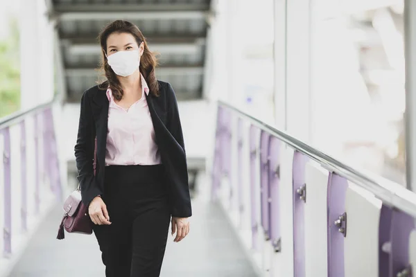オフィスで働くために街を歩く医療衛生保護マスクを身に着けている黒いスーツの美しいアジアの女性 健康管理のためのアイデアとコロナウイルスの流行のリスクを防ぐために — ストック写真