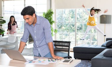 Karışık ırk ailesi bir arada kalıyor, anne mutfakta yemek ve içecek hazırlarken, beyaz baba masada çalışıyor ve küçük kız da bulanık bir şekilde kanepeye atlıyor, sıcak aile fikri..