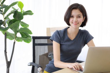 Genç, güzel ve güzel yarı yarış Taylandlı kız. Yatak odasında çalışan labrador bilgisayarını kullanırken masa gibi oturup gülümsüyor. Mutluluk fikri gençlerin okuduğu ve evden öğrendiği.