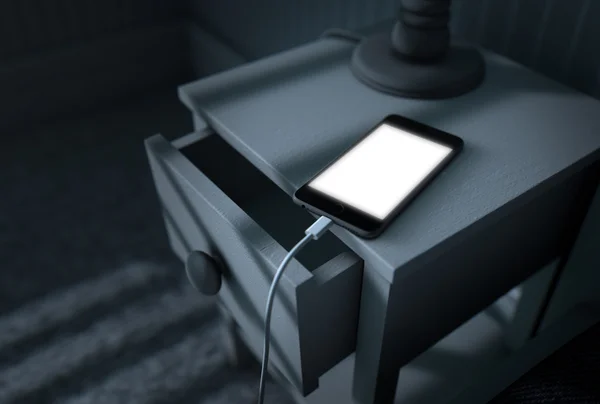 Освітлений мобільний телефон поруч з ліжком — стокове фото