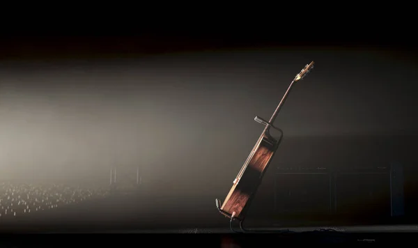 在一个音乐演奏台上的一个声乐吉他 由一个单一的戏剧聚光灯照亮 面对着灯光明亮的灯光 3D渲染 — 图库照片
