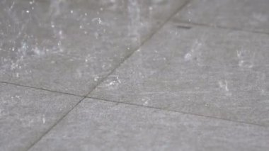 Yavaş hareket düşen yağmur gri karo zemin vurur. Hangi yağışlı sezon yalnız bir ruh verir, yağmur suyu tahıl yaymak için yere hareketi görmek.