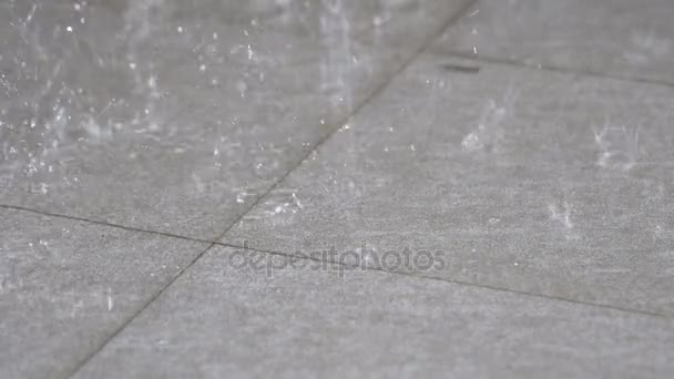 Het langzame deel van vallende regen raakt de grijze tegelvloer. Die geeft een eenzame bui in het regenseizoen, zie de beweging van regenwater op de vloer te verspreiden van de korrel. — Stockvideo